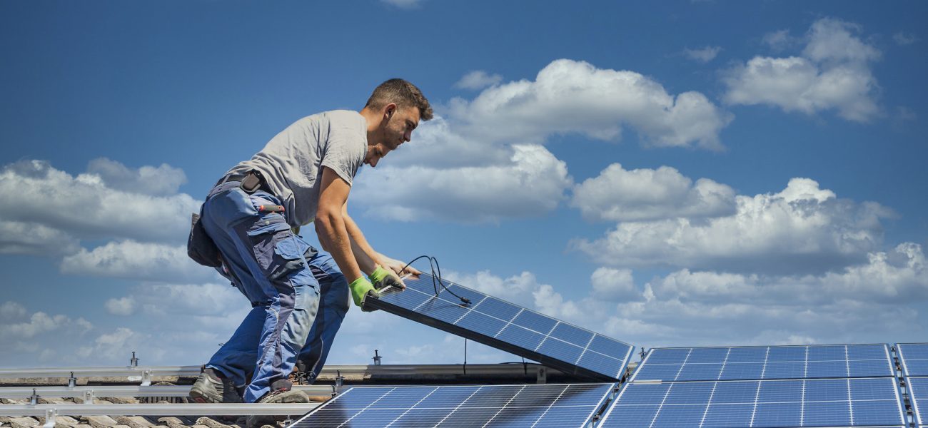 Installing solar photovoltaic panel system. Solar panel technician installing solar panels on roof. Alternative energy ecological concept.