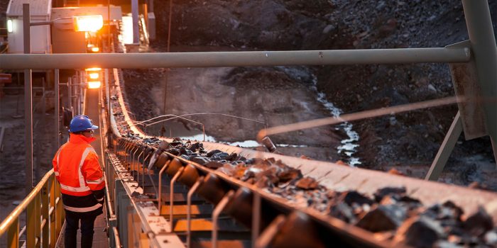 Nyngan Australia June 20th 2012 : Shallow depth of field image of a miner inspecting ore rocks on a conveyor in NSW Australia