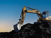 Coal mining in an open pit. Mining excavator loads coal in haul truck in quarry. Excavator digging in open pit coal mine. Excavator in open-pit on sunset background. Heavy machinery in opencast.