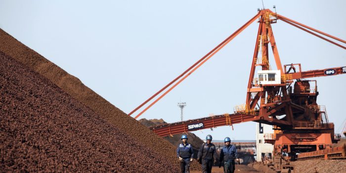 Workers walk by piles of iron ore at a transfer and storage center operated by the Shanghai International Port Group in Shanghai, China on 26 January 2010.   Xxx at the Yangshan deep-water port in Shanghai, China, on Tuesday, Jan. 26, 2010. 
Photographer: Qilai Shen/Bloomberg